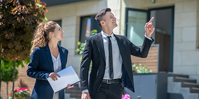 Image of a man and a woman in business suits looking at a real estate property