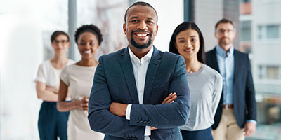 Image of five people in business attire with a man with folded arms in front and others behind him